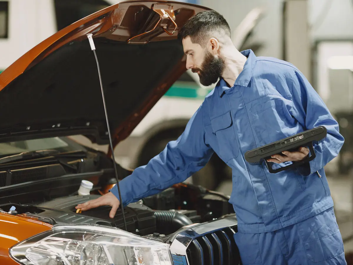 Mechanic checking a car engine with a diagnostic tablet