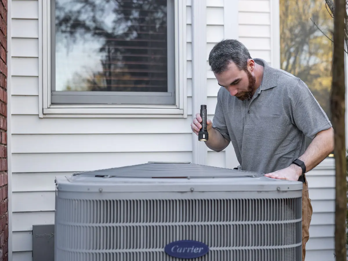 Technician inspecting a home's outdoor air conditioning unit