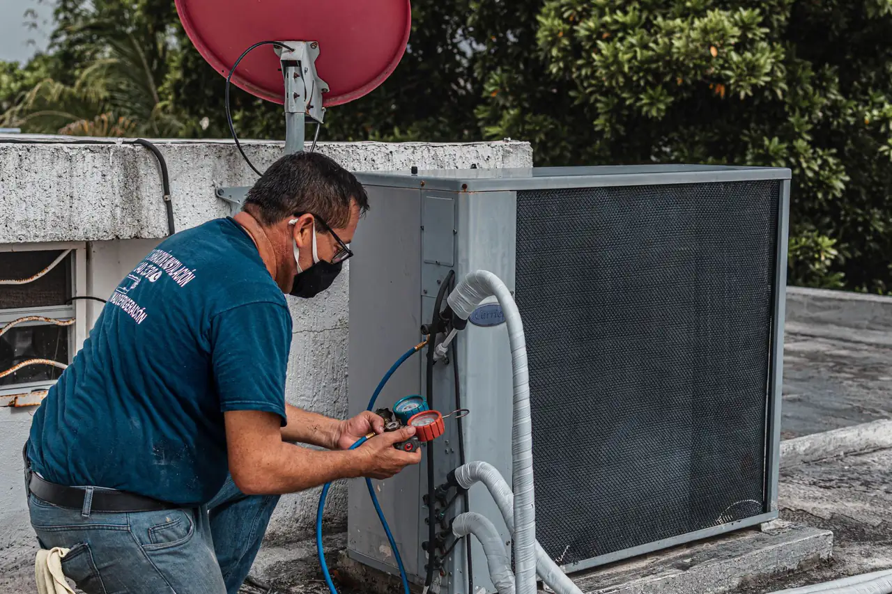 HVAC technician checking an air conditioning unit with refrigerant gauges