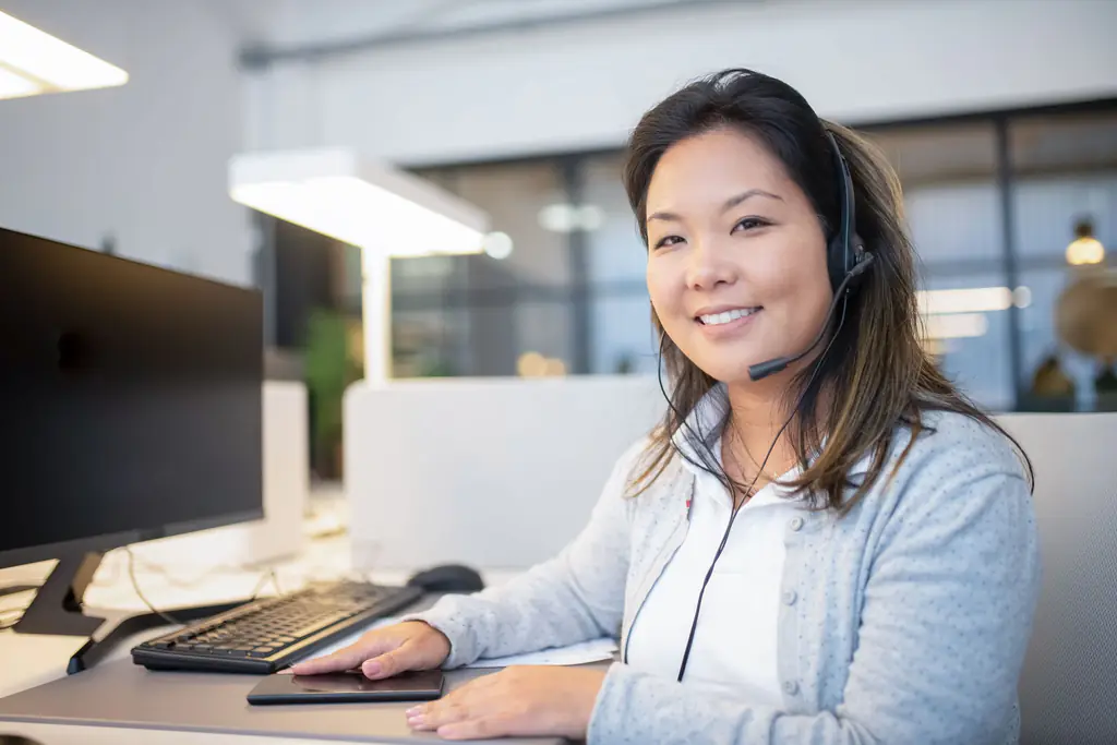 Smiling customer support advisor wearing a headset at her desk
